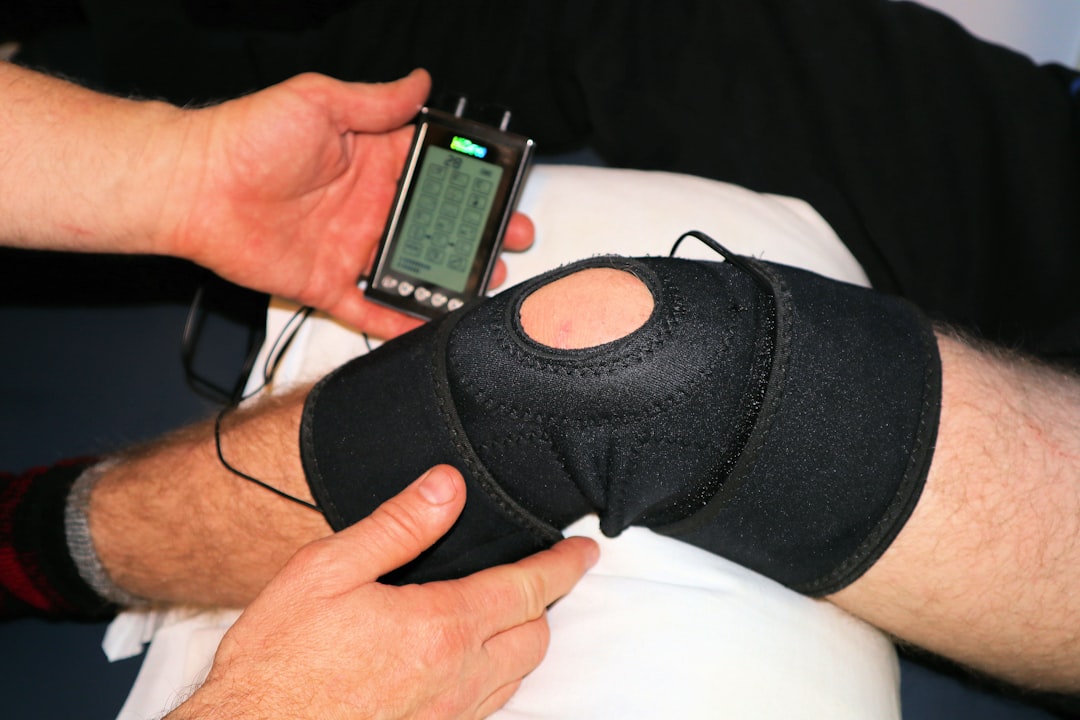 Cordless knee massager with heat and vibration — person holding black knit cap