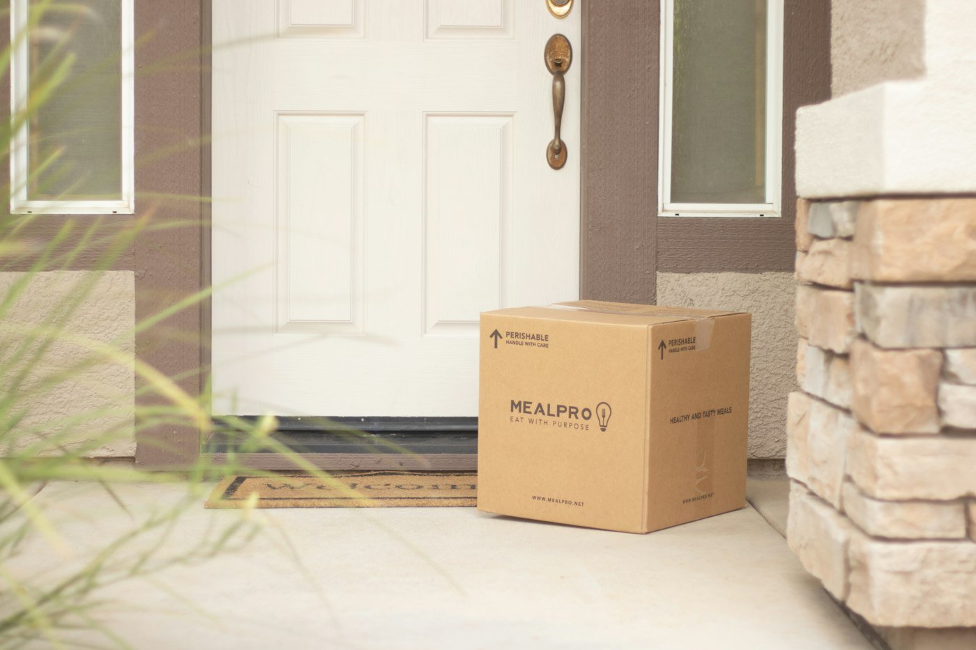 Cardboard box delivered beside a front door